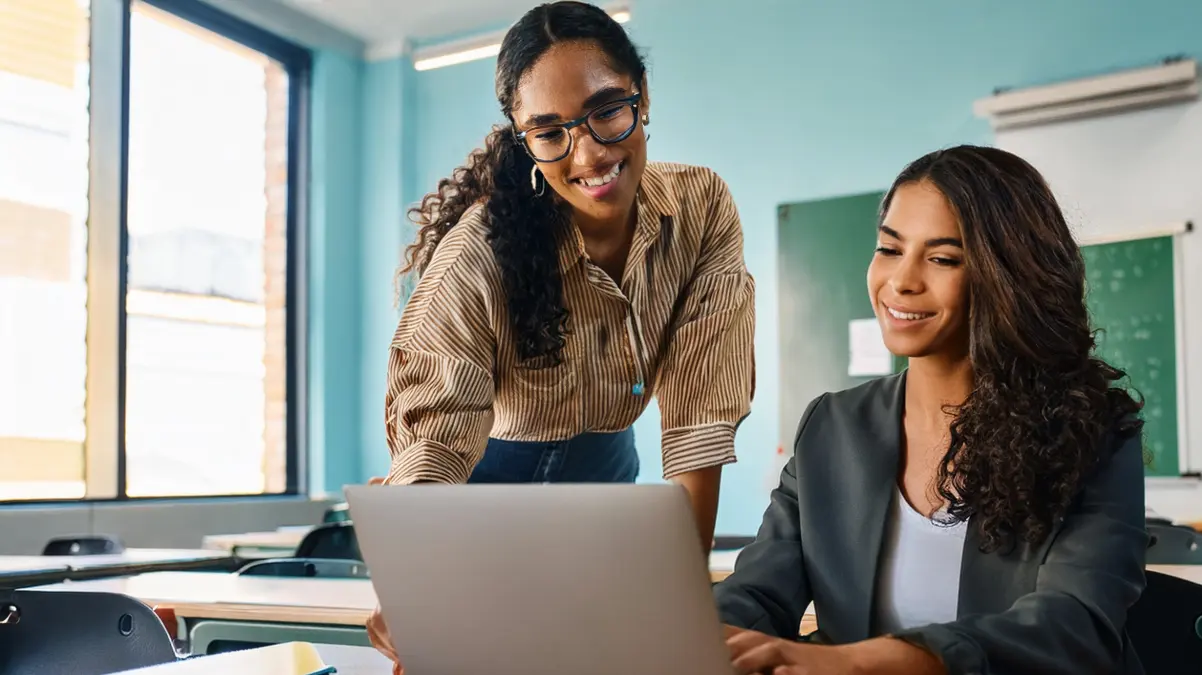 Student and teacher looking at laptop